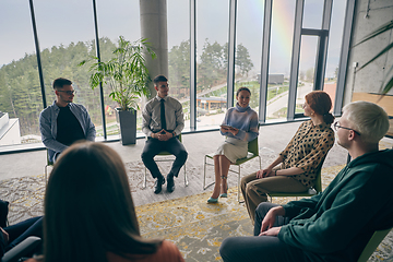 Image showing In a modern office, a diverse group of business individuals is seen gathered in a circle, engaged in lively discussions and sharing ideas about various business concepts.