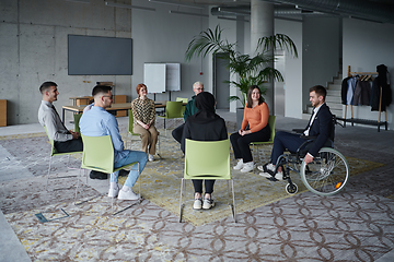 Image showing In a modern office, a diverse group of business individuals is seen gathered in a circle, engaged in lively discussions and sharing ideas about various business concepts.