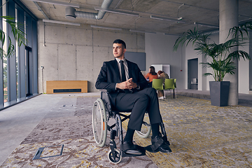 Image showing Businessman in a wheelchair commands attention, symbolizing resilience and success amidst a dynamic modern office environment.