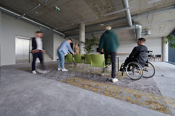 Image showing A businessman in a wheelchair sits at a table in a large, modern office, while his colleagues gather around, their steps blurred, symbolizing inclusivity, support, and unity in the face of challenges.