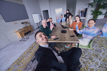 Image showing In a modern office, a group of businessmen gathers around a table during a meeting, capturing a moment of camaraderie and teamwork as they take a selfie