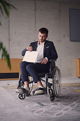 Image showing A businessman with disability in a wheelchair using laptop in a modern office