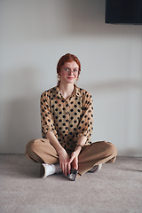 Image showing A young and fashionable businesswoman sitting and taking a moment to relax while using her smartphone.