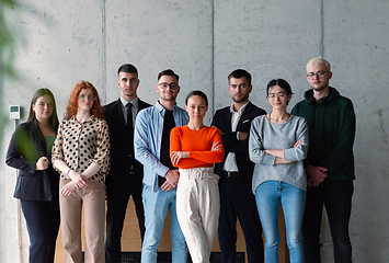 Image showing A diverse group of successful businesspeople gather and pose for a photo, showcasing teamwork and professional empowerment in a modern office setting.