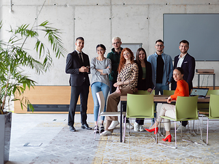 Image showing A diverse group of successful businesspeople gather and pose for a photo, showcasing teamwork and professional empowerment in a modern office setting.