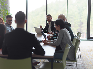 Image showing A diverse group of business professionals, including an person with a disability, gathered at a modern office for a productive and inclusive meeting.