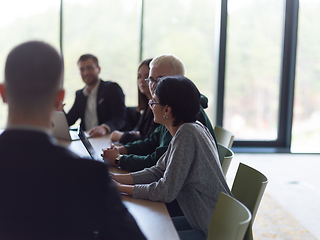 Image showing A diverse group of business professionals, including an person with a disability, gathered at a modern office for a productive and inclusive meeting.