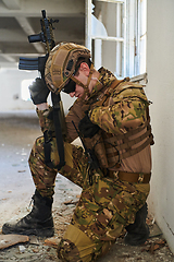 Image showing Soldier in action near window changing magazine and take cover