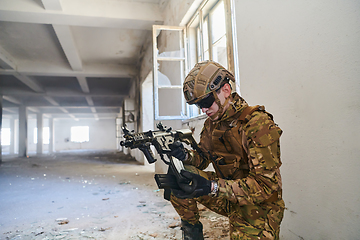 Image showing Soldier in action near window changing magazine and take cover