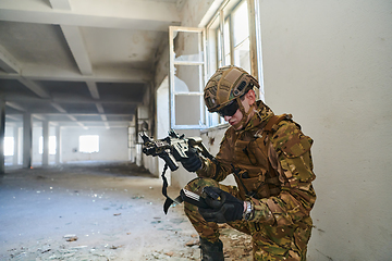 Image showing Soldier in action near window changing magazine and take cover