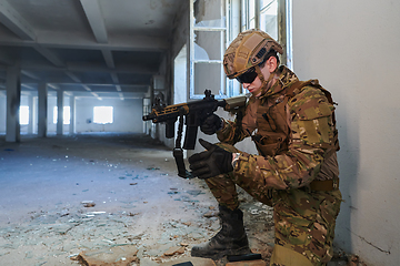 Image showing Soldier in action near window changing magazine and take cover