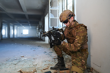 Image showing Soldier in action near window changing magazine and take cover