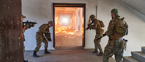 Image showing A group of professional soldiers bravely executes a dangerous rescue mission, surrounded by fire in a perilous building.