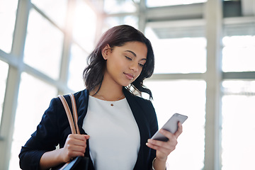 Image showing Success tip Always be reachable. an attractive young businesswoman using a smartphone while standing in a modern office.