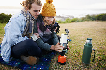 Image showing Lets get this coffee warmed up. a young couple warming up a pot of coffee outdoors.