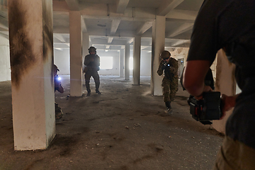 Image showing A professional cameraman captures the intense moments as a group of skilled soldiers embarks on a dangerous mission inside an abandoned building, their actions filled with suspense and bravery