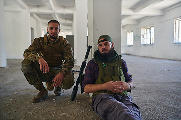 Image showing Group of soldiers discusses military tactics while situated in an abandoned building, meticulously planning their moves with focus and determination.