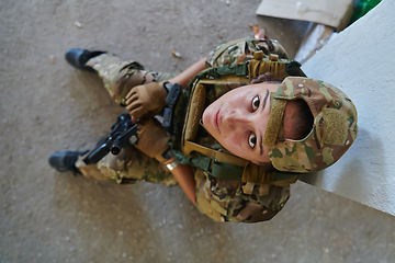 Image showing A woman in a professional military uniform sits in an abandoned building, ready for a dangerous mission, exuding bravery and determination