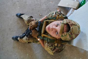 Image showing A woman in a professional military uniform sits in an abandoned building, ready for a dangerous mission, exuding bravery and determination