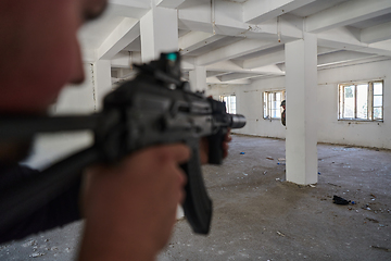 Image showing In an abandoned building, a terrorist takes aim with a rifle at a military opponent, engaged in a fierce battle for territorial control, embodying the dangers and tensions of the conflict.