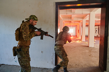 Image showing A group of professional soldiers bravely executes a dangerous rescue mission, surrounded by fire in a perilous building.