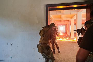 Image showing A group of professional soldiers bravely executes a dangerous rescue mission, surrounded by fire in a perilous building.