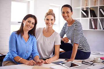 Image showing Our new company is thriving. Three confident young businesswomen smiling at the camera.