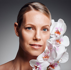 Image showing Beautiful mature woman posing with flowers in studio against a grey background