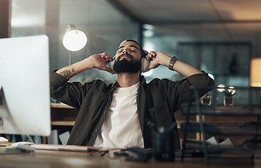 Image showing Calming sounds take care of late night stress. a young businessman using headphones during a late night at work.