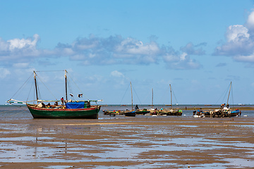 Image showing Fishing boat stranded on the dry port during low tide with Malagasy people around.