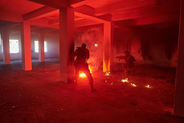 Image showing A group of professional soldiers bravely executes a dangerous rescue mission, surrounded by fire in a perilous building.