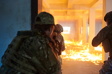 Image showing A group of professional soldiers bravely executes a dangerous rescue mission, surrounded by fire in a perilous building.