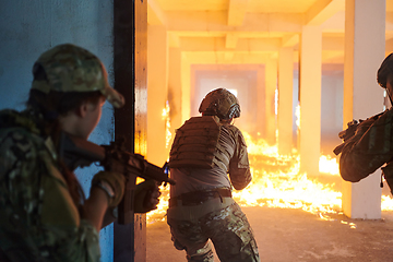 Image showing A group of professional soldiers bravely executes a dangerous rescue mission, surrounded by fire in a perilous building.