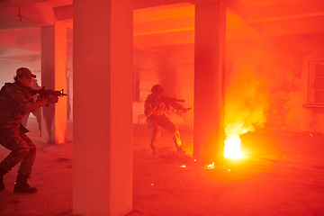 Image showing A group of professional soldiers bravely executes a dangerous rescue mission, surrounded by fire in a perilous building.