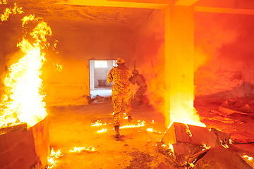 Image showing A group of professional soldiers bravely executes a dangerous rescue mission, surrounded by fire in a perilous building.