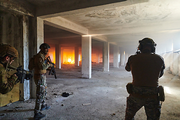 Image showing A group of professional soldiers bravely executes a dangerous rescue mission, surrounded by fire in a perilous building.