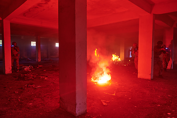 Image showing A group of professional soldiers bravely executes a dangerous rescue mission, surrounded by fire in a perilous building.