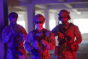 Image showing Soldier squad team walking in urban environment colored lightis