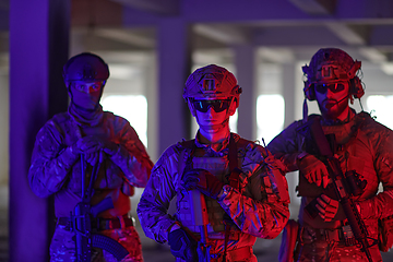 Image showing Soldier squad team walking in urban environment colored lightis