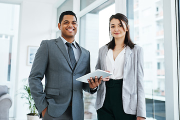 Image showing Whatever needs to be done, digital tech’s got us covered. a young businessman and businesswoman using a digital tablet in a modern office.