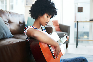 Image showing I found a new hobby. a young woman playing the guitar while sitting at home.