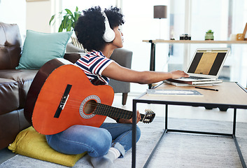 Image showing This song needs a bit of tweaking. a woman using her laptop while playing the guitar at home.