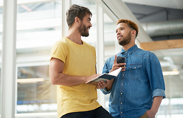 Image showing Staying organised at work can be useful for your productivity. two businessmen going through a notebook together in an office.