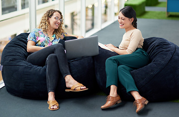 Image showing Maintaining innovation through their collaboration. two businesswomen using a laptop together while sitting on beanbags in an office.