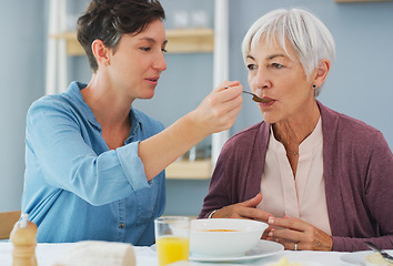 Image showing Isnt this delicious Mum. an attractive young woman helping and feeding her senior mother while they have breakfast together at home.