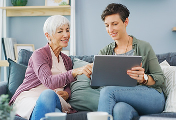 Image showing Can we watch this later. an attractive young woman sitting with her happy senior mother and using a tablet while at home.