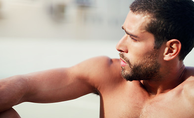 Image showing Taking a much needed breather. a handsome shirtless young sportsman sitting down while taking a break after a workout outdoors.