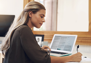 Image showing Pouring in hours and hours of dedication into her business. a young businesswoman going through paperwork while using a laptop in an office.