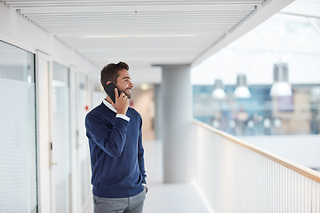 Image showing Stepping out to make a follow-up call with a client. a young businessman talking on a cellphone in an office.