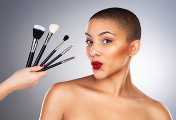 Image showing Theres a wand for every kind of magic. Studio shot of a hand holding makeup brushes next to a beautiful young womans face.